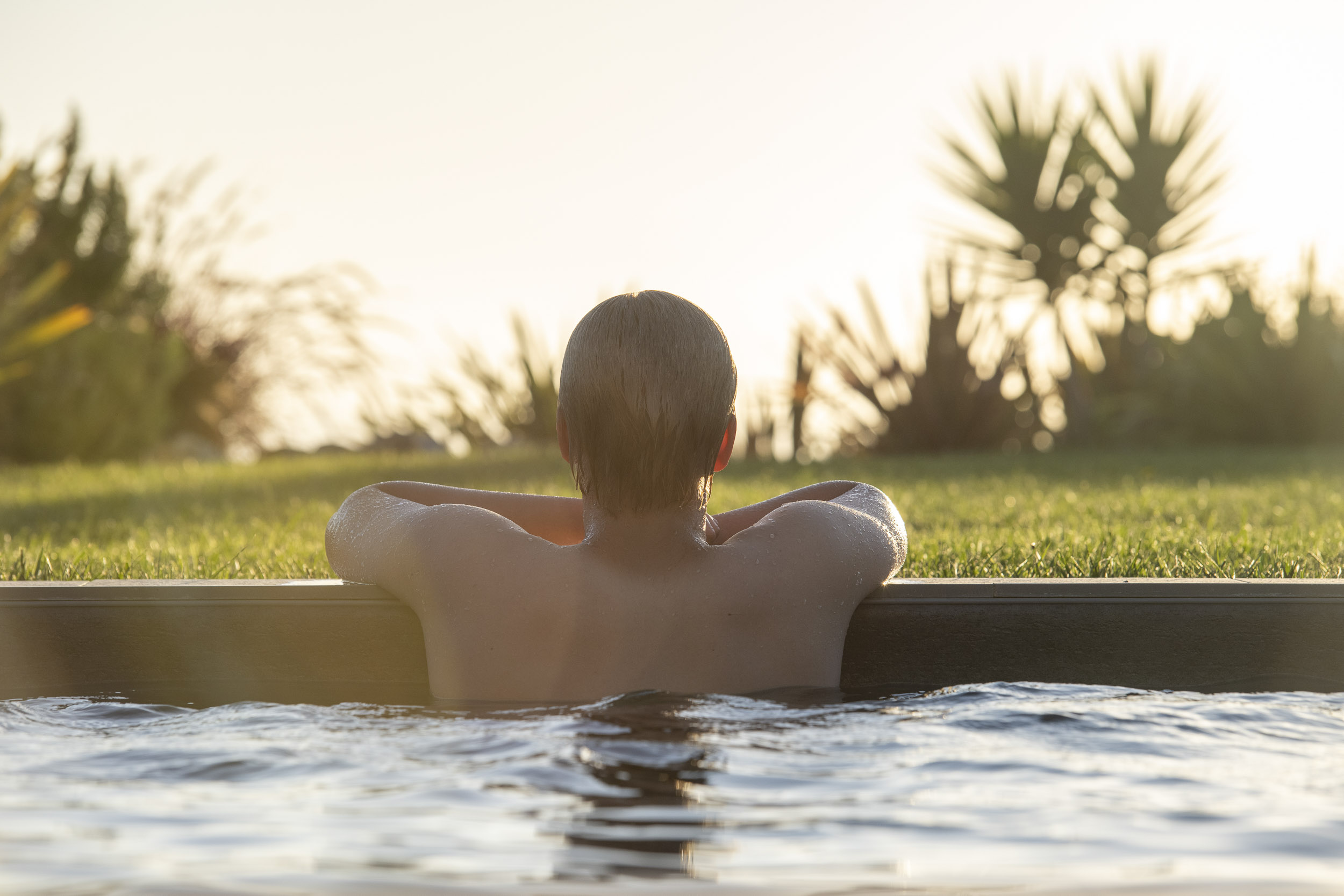 Young man relaxing in pool at sunset